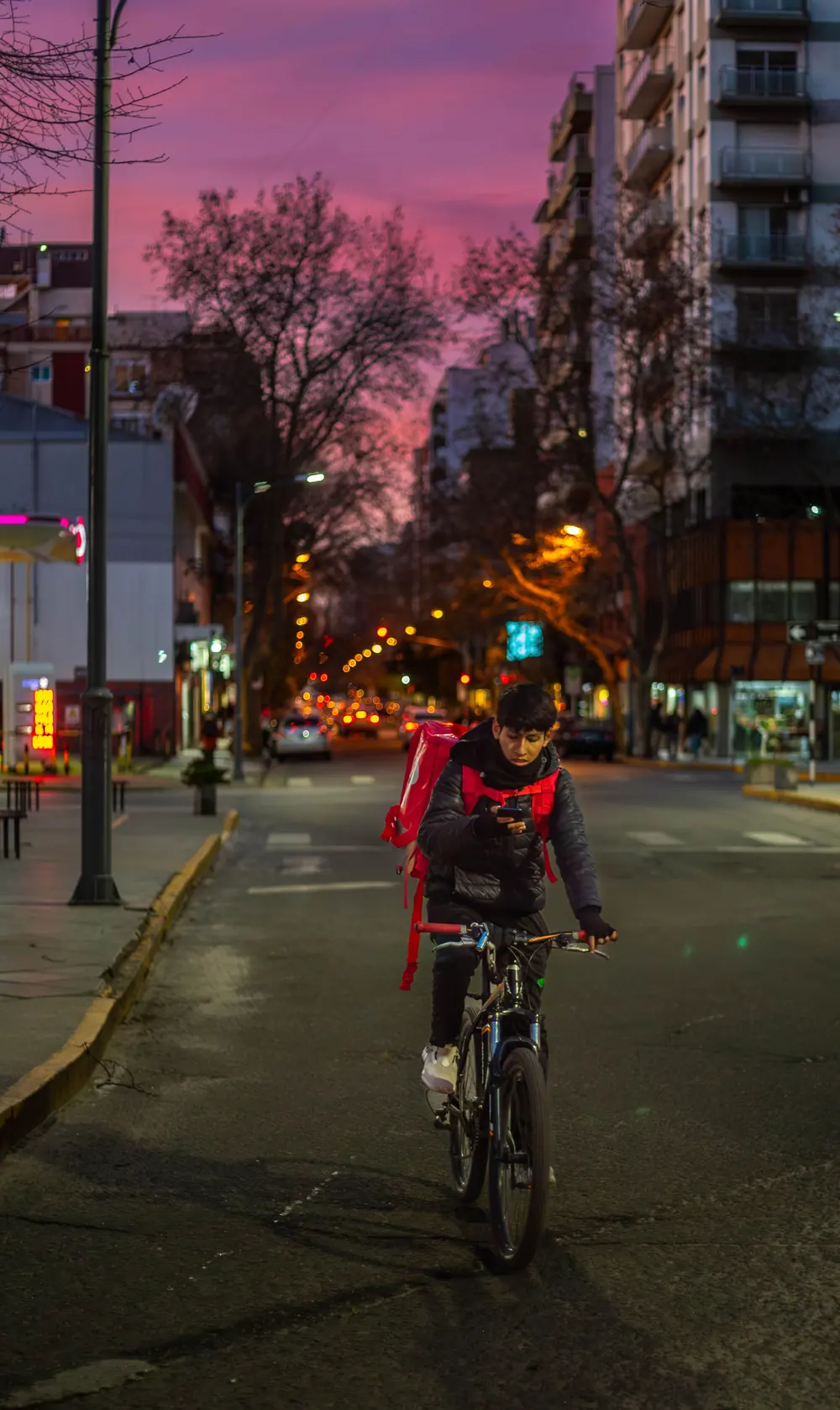Repartidor en bicicleta de noche con mochila de entrega